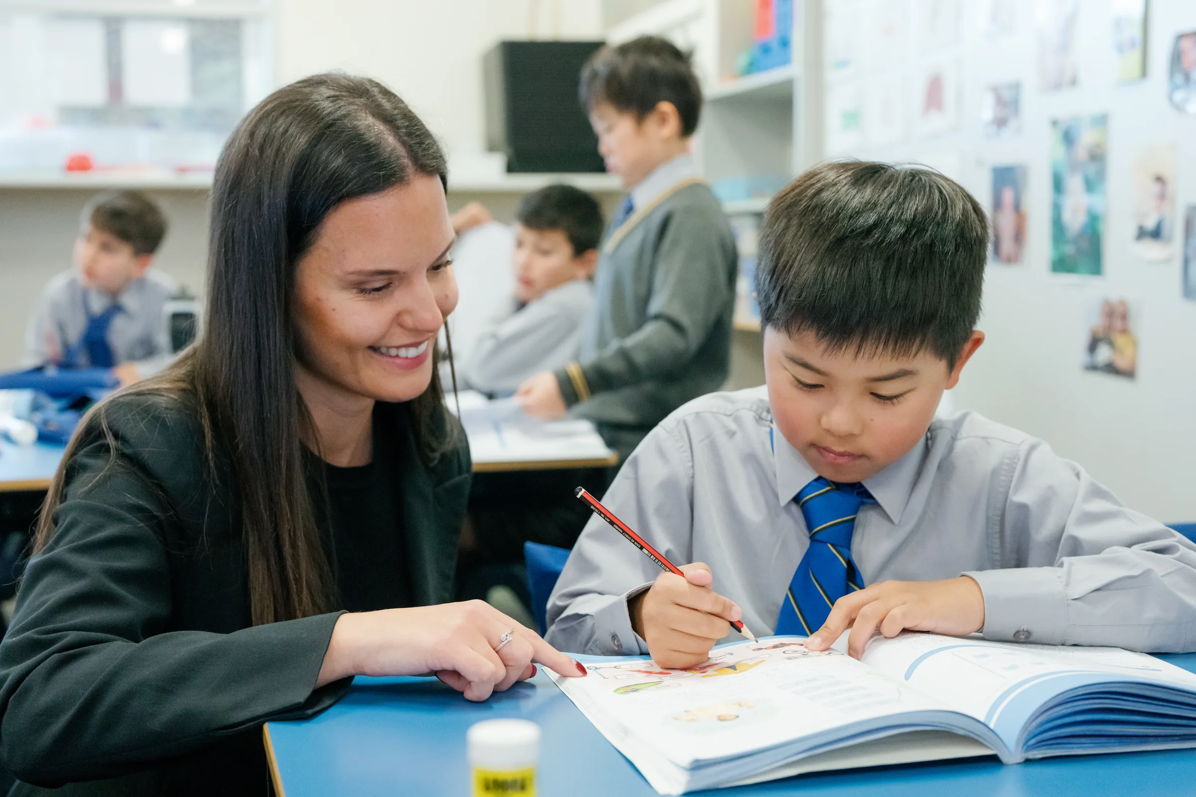 A Coogee Prep teacher working through a book with a boy at his desk