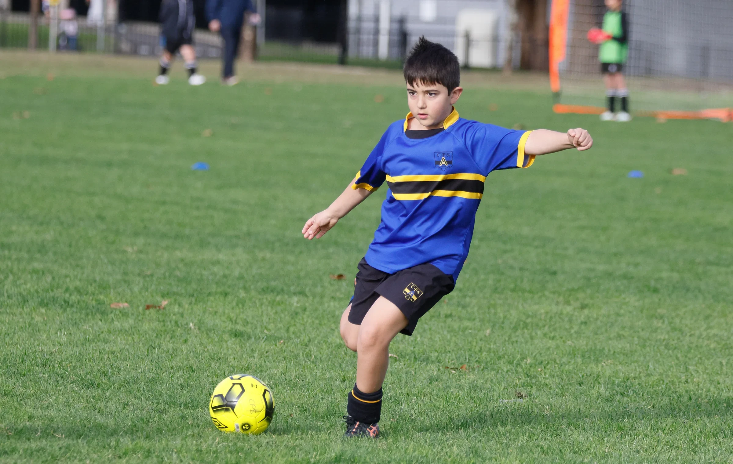 A Coogee Prep boy playing football in the school's blue and gold
