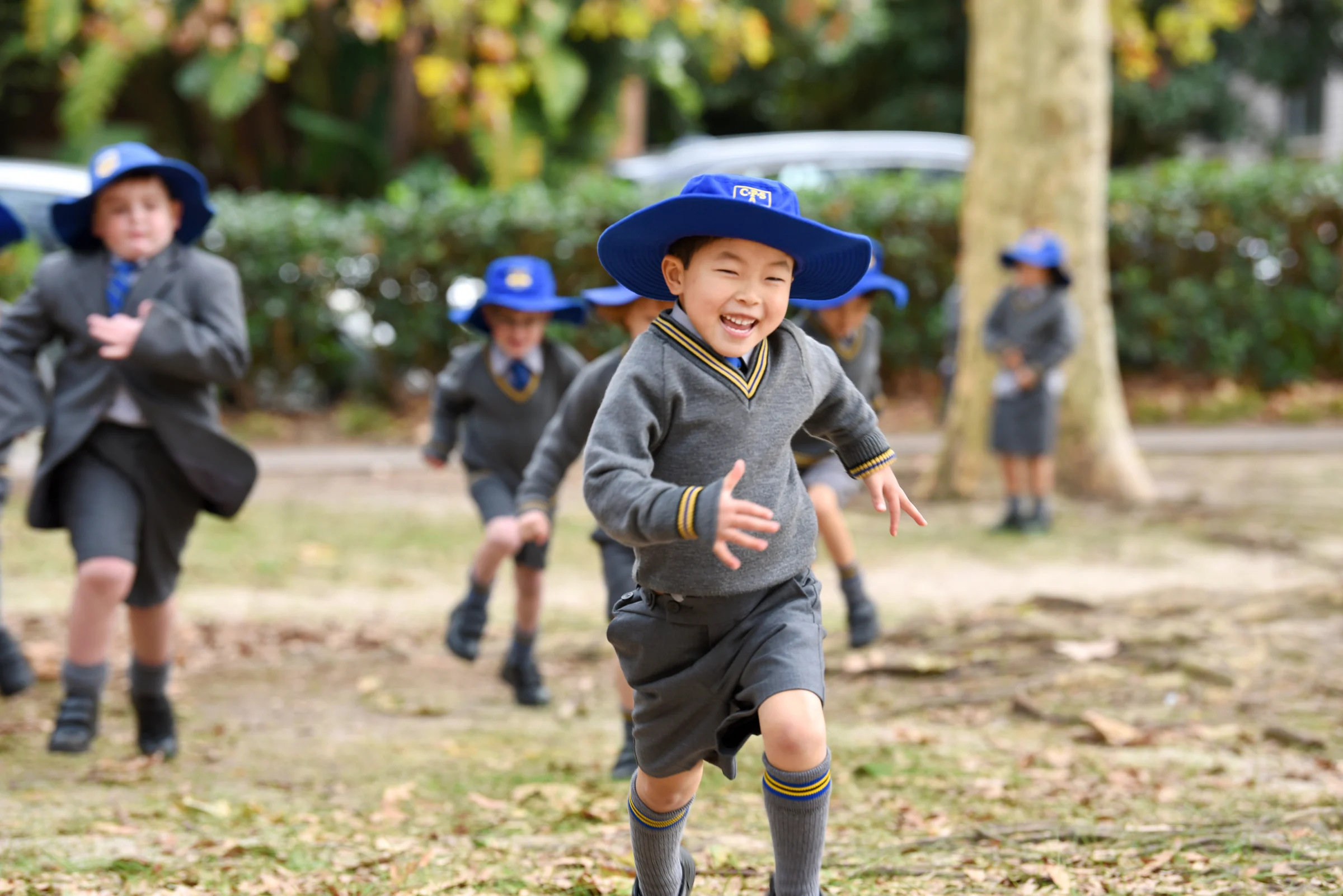 Coogee Prep boys in school hats running and playing outdoors