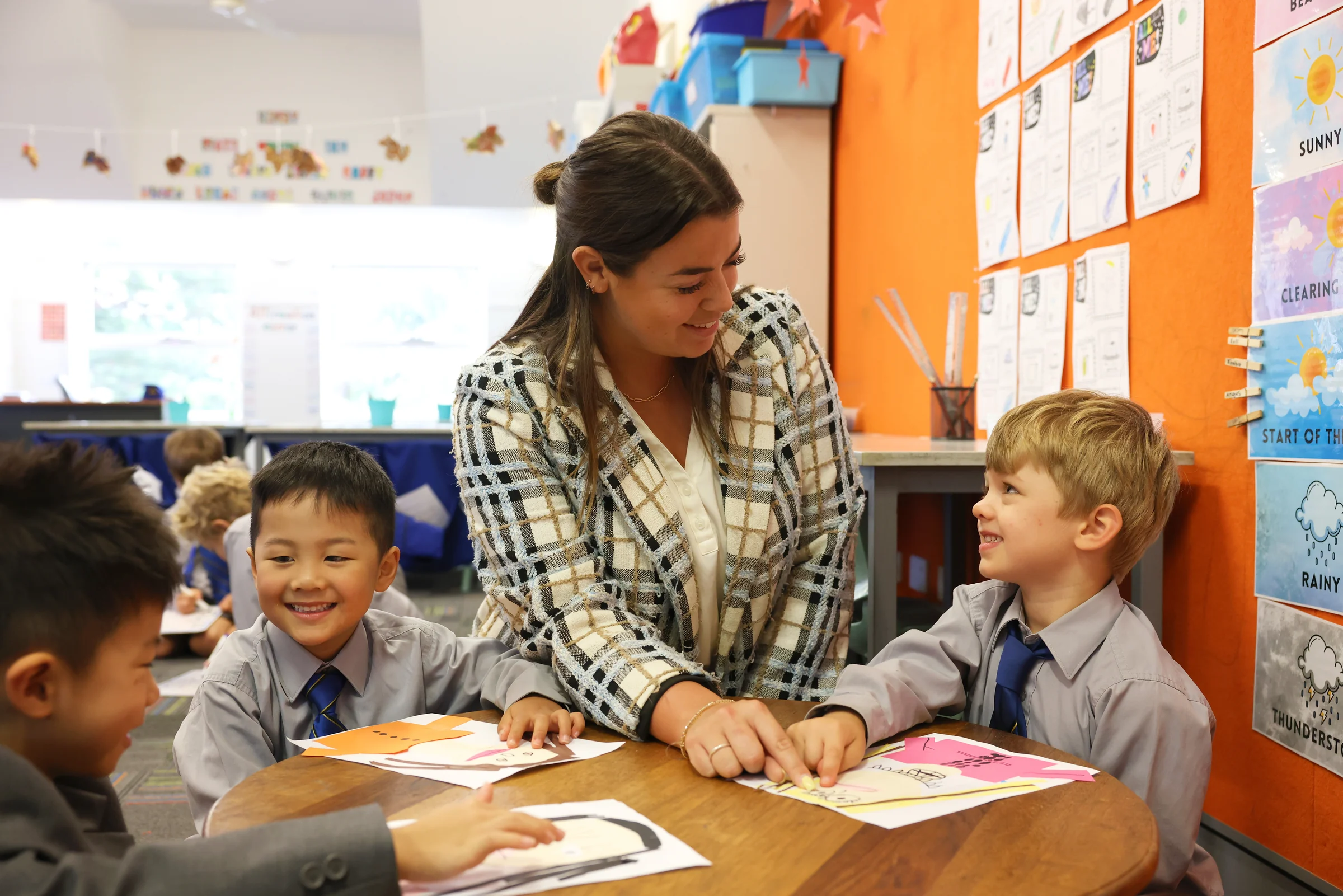 A Coogee Prep teacher working with two boys at a classroom table