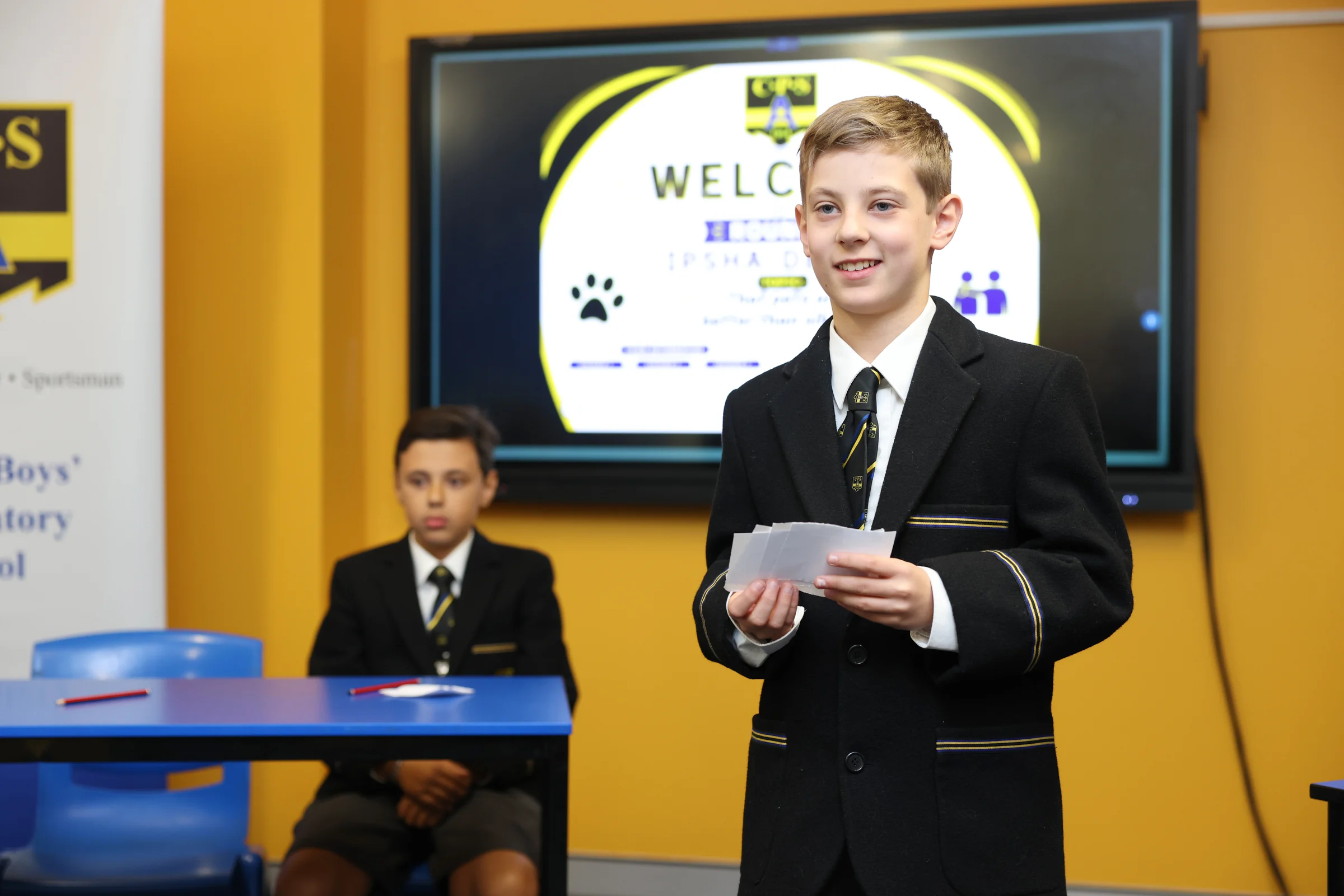 A senior Coogee Prep boy presenting to his class beside a screen